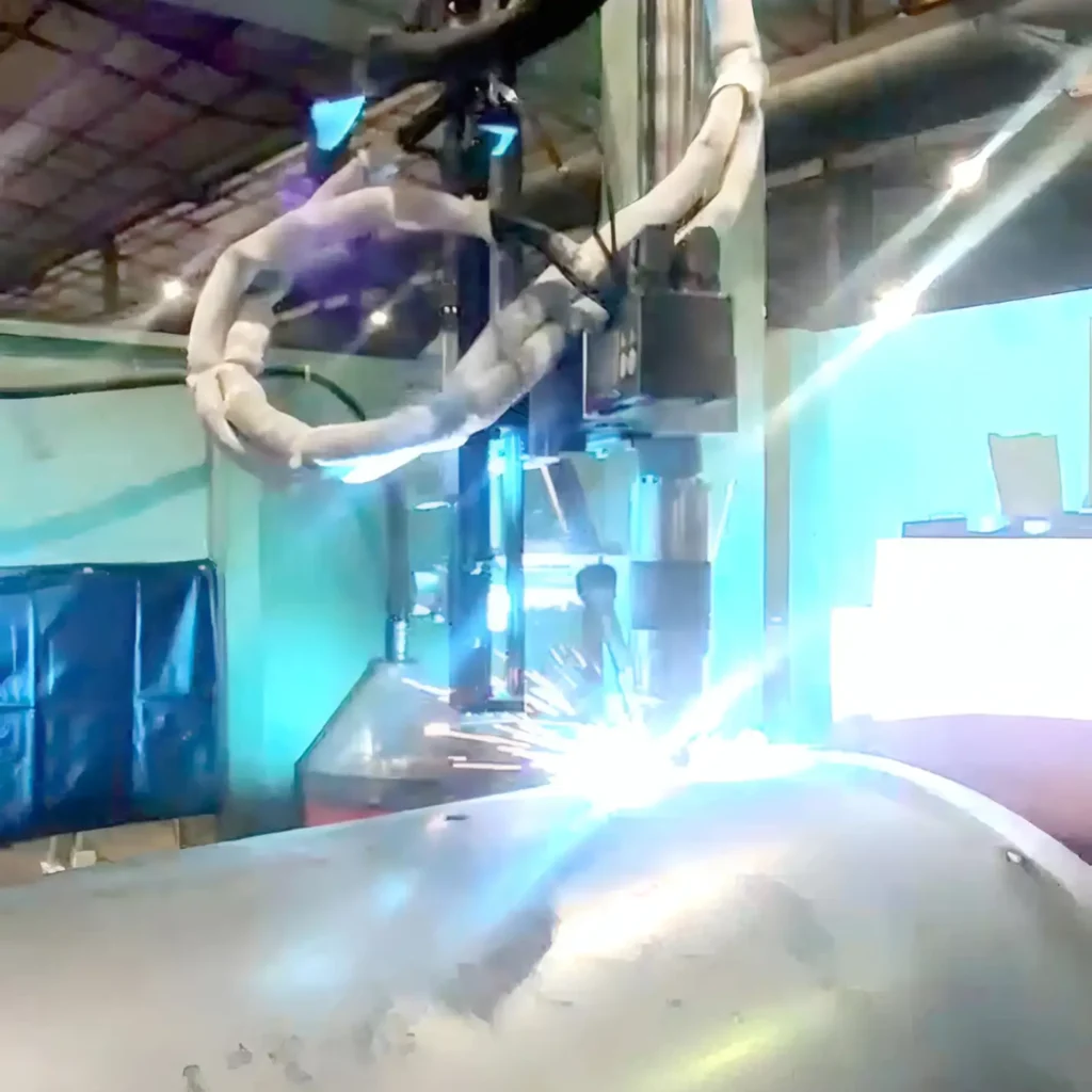 Industrial robotic arm welding at a production line with bright sparks near a steel surface.